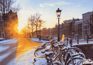Grachtenstraat met besneeuwde fietsen in de winter, typisch Nederlands stadsbeeld