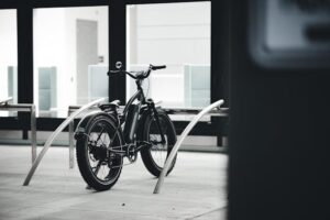 Elektrische fiets op slot in een fietsenrek bij een modern gebouw, symbool voor het belang van fietsverzekering tegen diefstal.