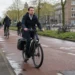 Forens op elektrische fiets onderweg naar werk op een Nederlands fietspad.